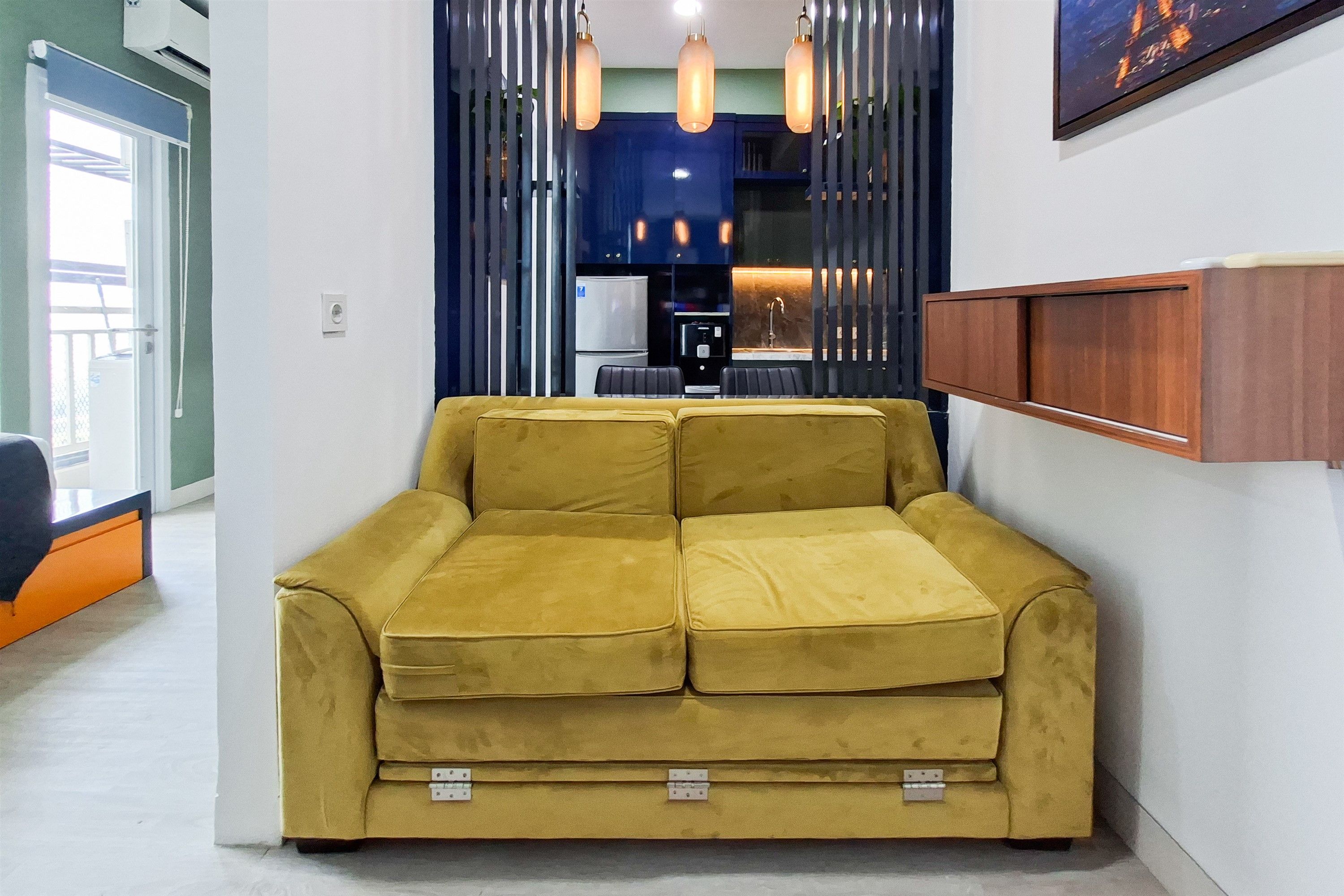 A yellow sofa in a modern room with a kitchen area in the background.