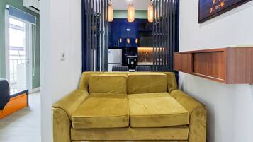A yellow sofa in a modern room with a kitchen area in the background.
