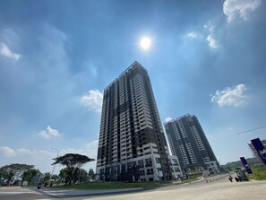 A tall residential building with multiple floors and balconies, surrounded by a clear sky and a few clouds. - Upscale And Elegant Studio Apartment Meikarta District 2 (Cikarang)
