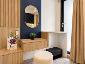 A modern bathroom with a wooden vanity, a round mirror, a potted plant, and a magazine on the counter. - Upscale And Elegant Studio Apartment Meikarta District 2 (Cikarang)