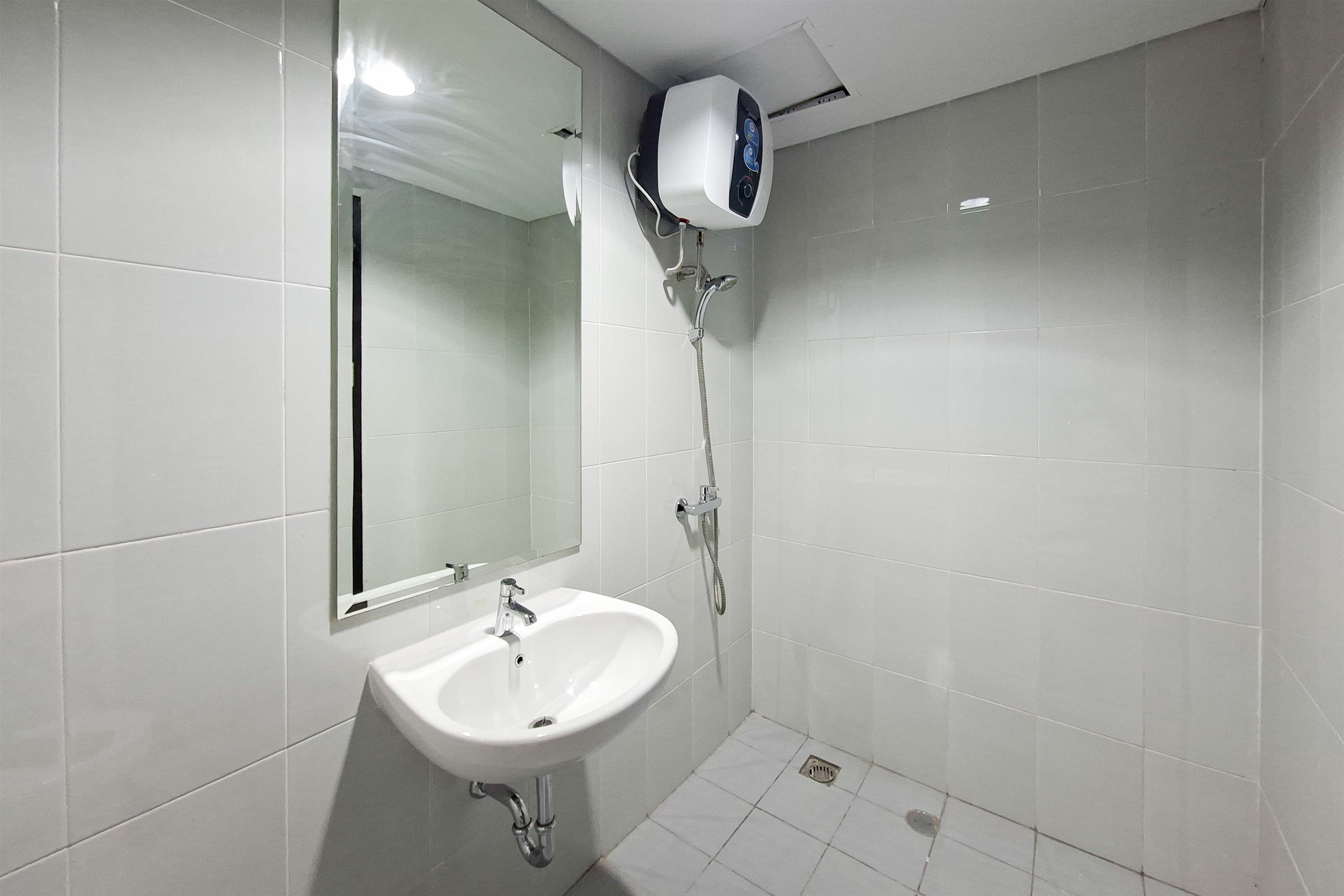 Un baño con lavamanos blanco, un espejo y un cabezal de ducha.