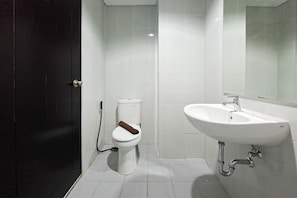 Ein Badezimmer mit Toilette, Waschbecken und einer dunklen Tür.