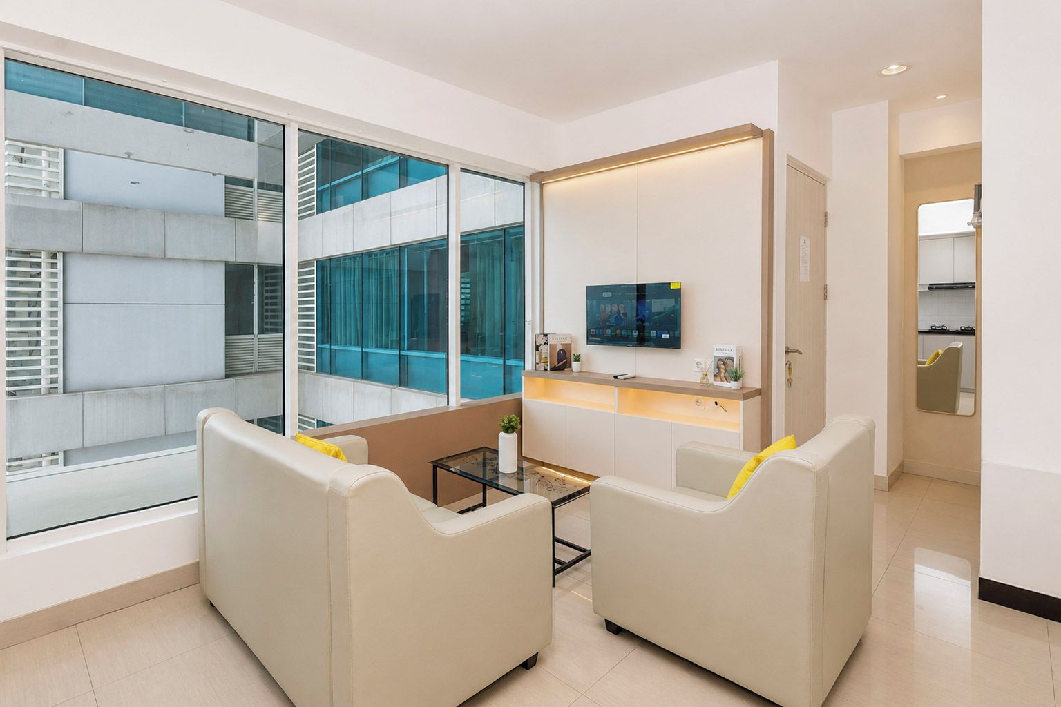 Una sala de estar moderna con un sofá, una mesa de centro y un televisor montado en la pared.