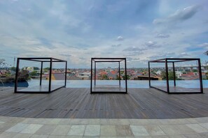 A rooftop terrace with a wooden deck and three glass-enclosed structures. - Comfortable 2Br At Apartment Grand Kamala Lagoon (Bekasi)