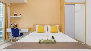 A modern hotel room with a bed, a desk, and a wardrobe.