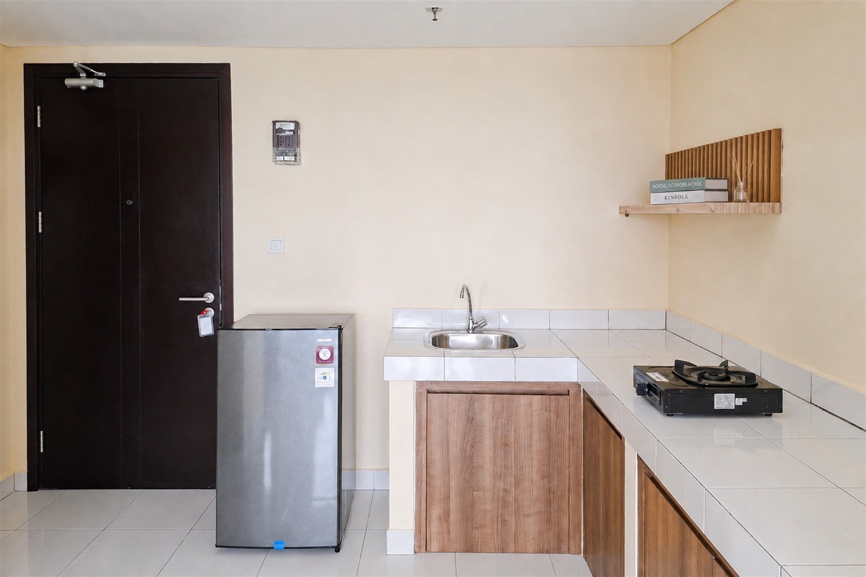 Cocina compacta con refrigerador, pileta y una pequeña mesada.