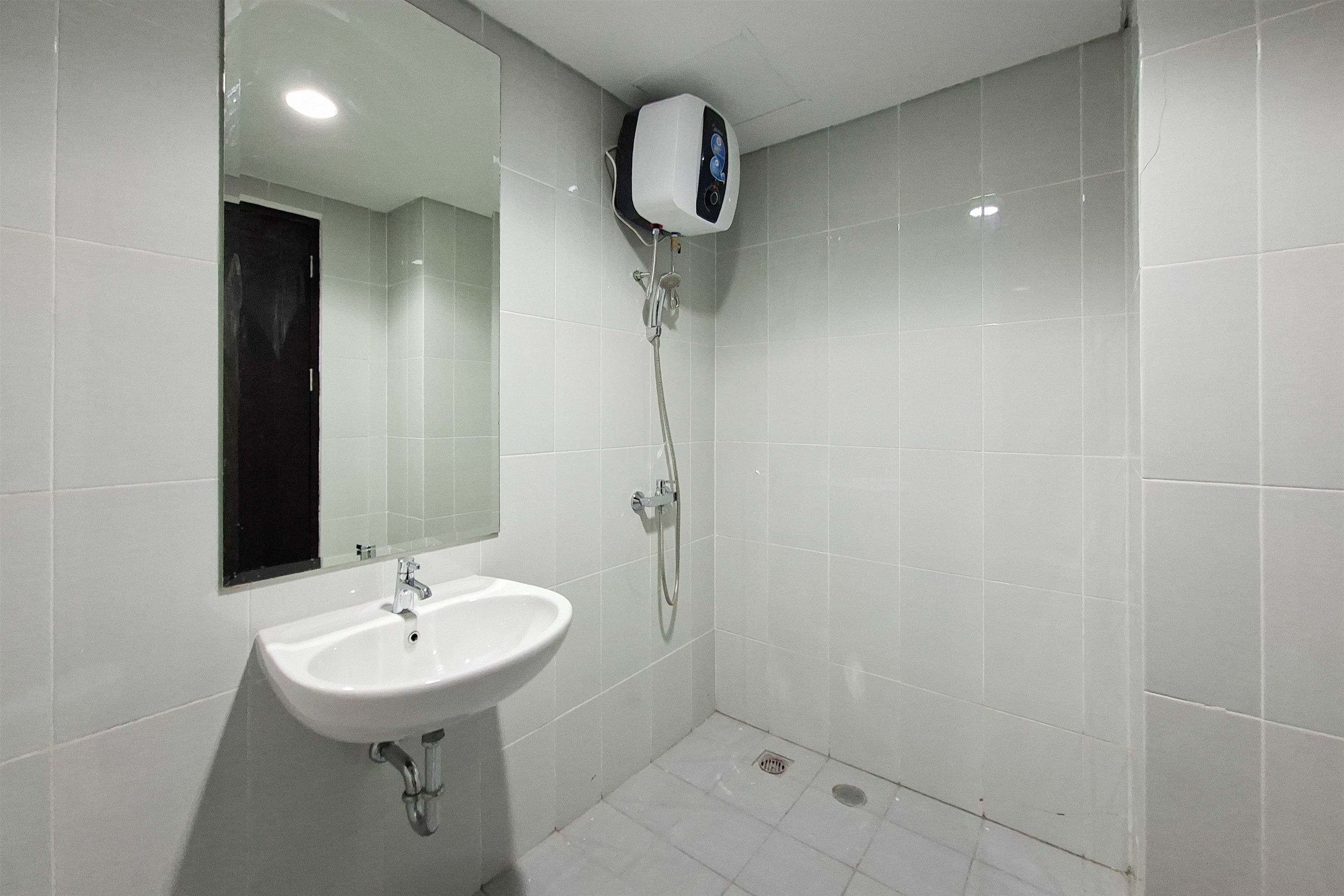 Un baño con lavamanos blanco, un espejo y un cabezal de ducha manual.
