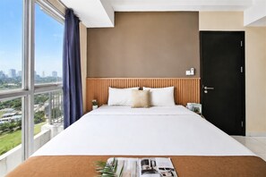 Ein Hotelzimmer mit einem großen Bett, einem Holzkopfteil, Blick auf die Stadt und einer schwarzen Tür.