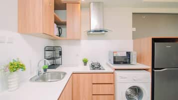 A modern kitchen with wooden cabinets, a stainless steel sink, a microwave, a refrigerator, and a washing machine.