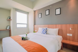 Une chambre d’hôtel moderne avec un grand lit, une table de chevet, une fenêtre et un mur décoré de tableaux encadrés.