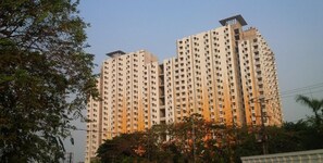 A high-rise residential building with multiple balconies, surrounded by trees and under a clear sky. - Good And Homey 2Br At Apartment Kemang View (Bekasi)