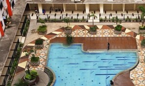 An outdoor swimming pool with a tiled deck area, surrounded by potted plants and a covered seating area. - Good And Homey 2Br At Apartment Kemang View (Bekasi)
