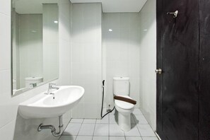A bathroom with a white sink, a toilet, and a dark door. - Nice And Restful Studio Room At Apartment Casa De Parco (Tangerang)