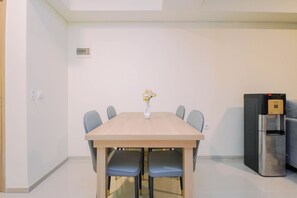 Ein Essbereich mit einem Holztisch, sechs Stühlen, einer Blumenvase und einem Kühlschrank.