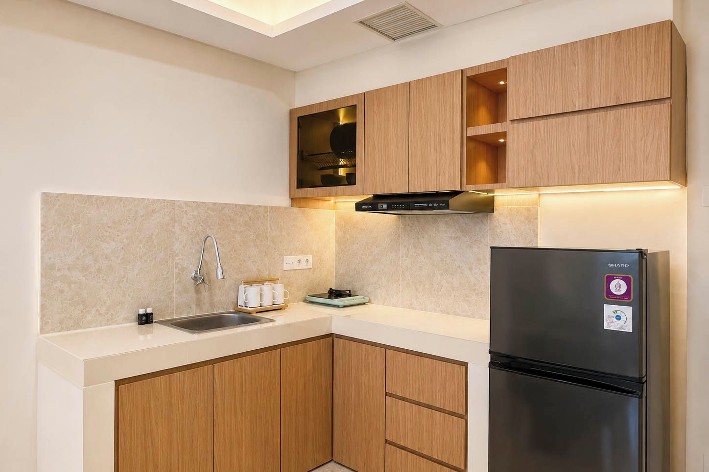 Una cocina moderna con armarios de madera, un refrigerador de acero inoxidable y un horno empotrado.