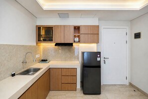 Una cocina moderna con horno empotrado, pileta y alacenas de madera.