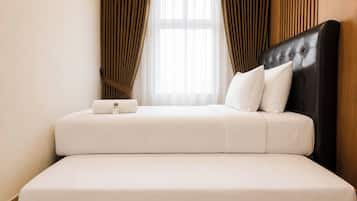 A hotel room with a bed, a control panel, and a window with curtains.