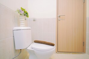 Ein Badezimmer mit Toilette, einem Handtuch und einer Holztür.
