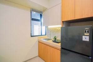 A compact kitchen with wooden cabinets, a stainless steel refrigerator, a window with blinds, and a marble countertop. - Bright And Modern 2Br At Apartment Meikarta District 2 (Cikarang)