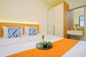 Ein Hotelzimmer mit einem Bett, einem Nachttisch mit Blumenvase und einem Spiegel darüber.
