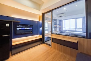 Une chambre d’hôtel moderne, dotée d’un grand lit, d’une télévision et offrant une vue sur la ville grâce à une grande fenêtre.