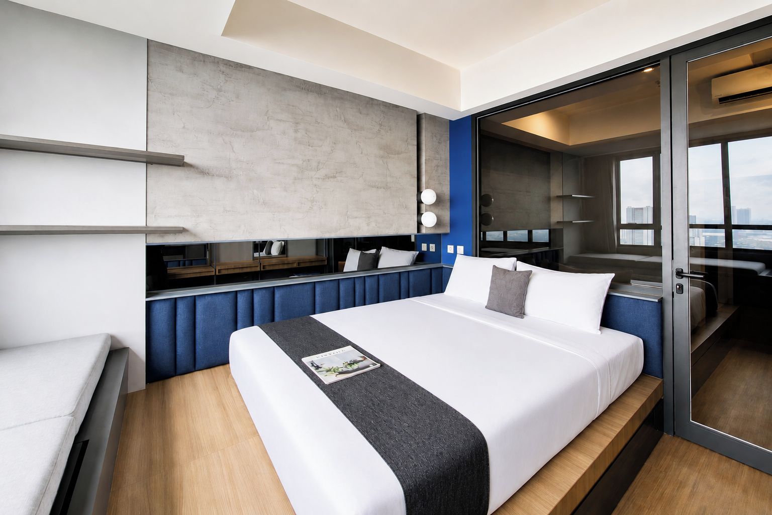 A modern hotel room with a large bed, a seating area, and a view of the city.