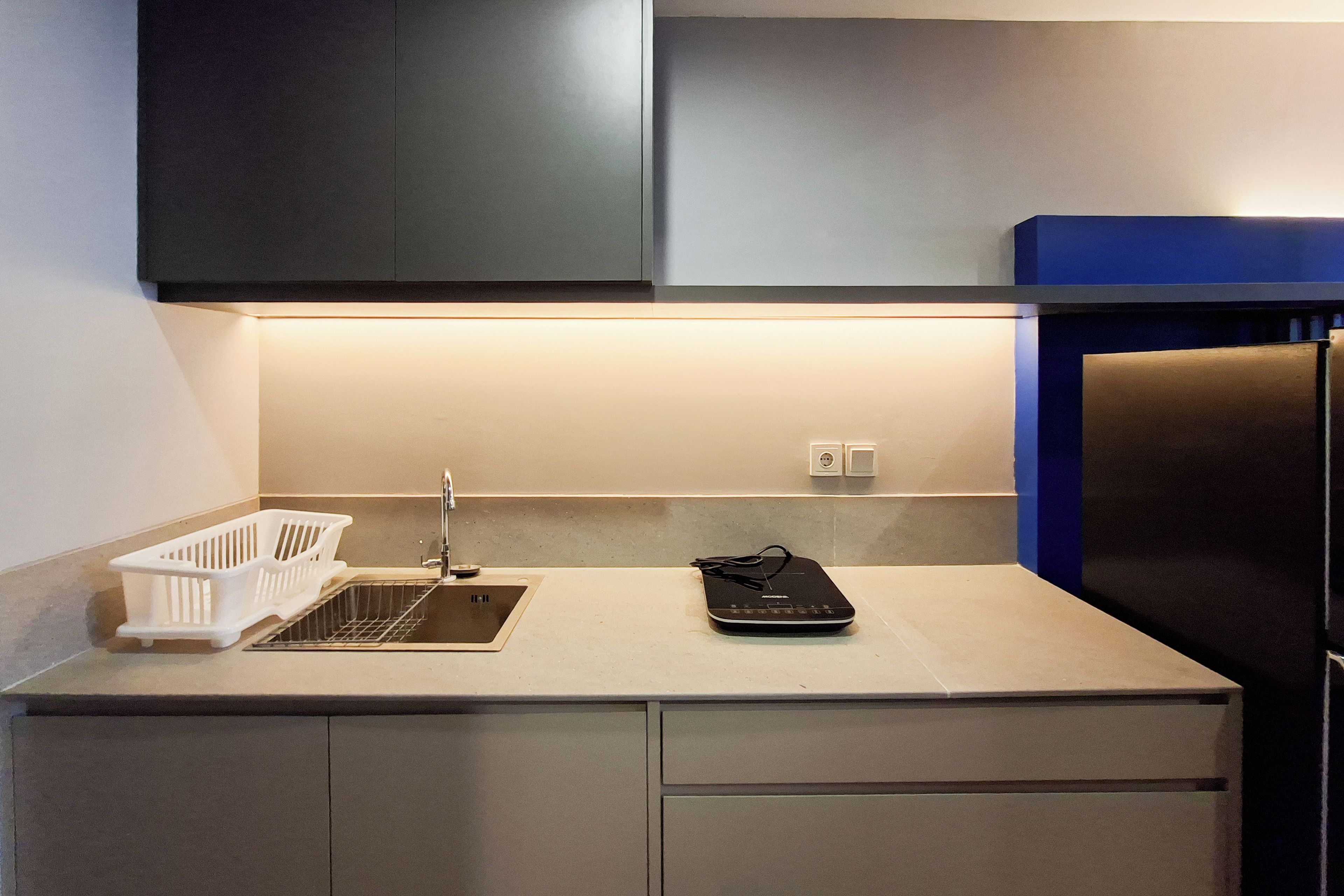 A kitchen with a white countertop, a black appliance, and a white dish rack.