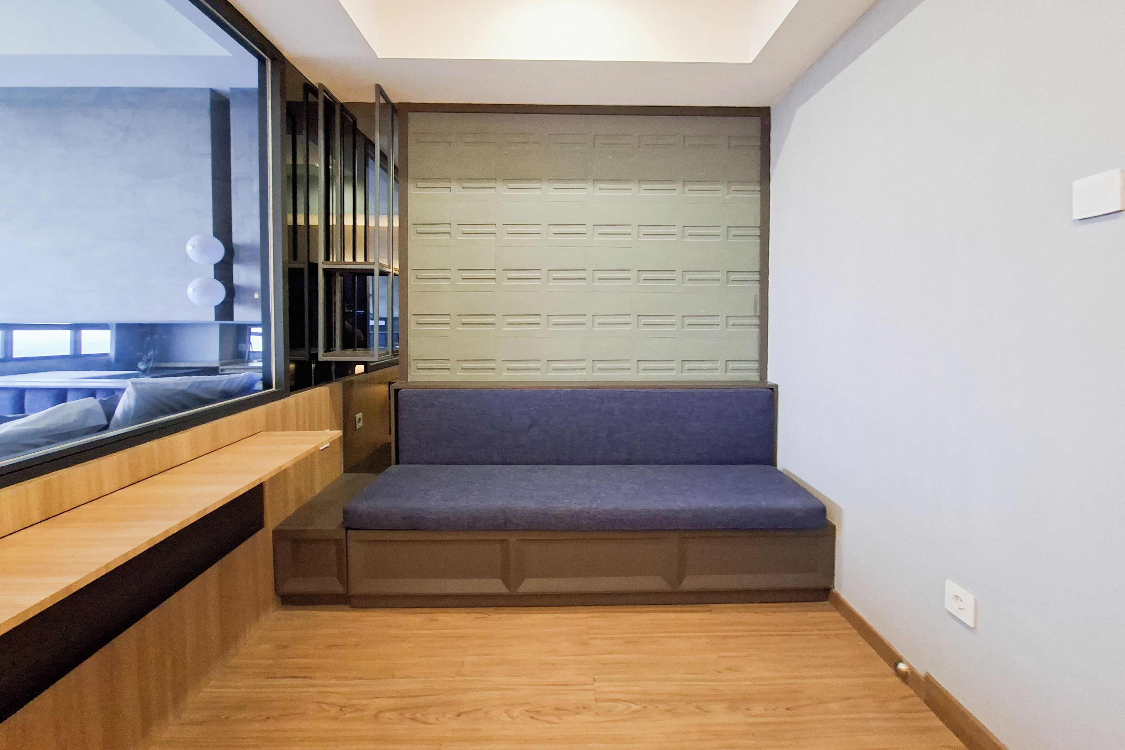 A modern room with a built-in bench, a window with blinds, and a wooden floor.