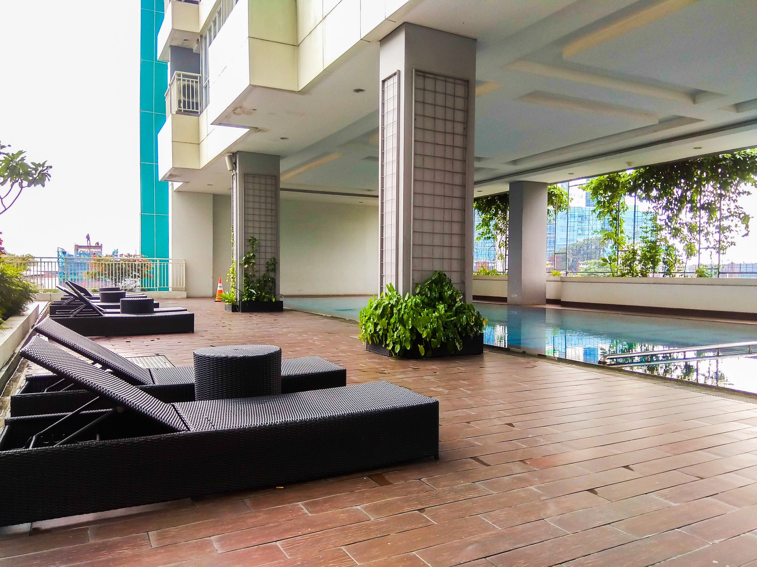A rooftop pool area with lounge chairs and potted plants.
