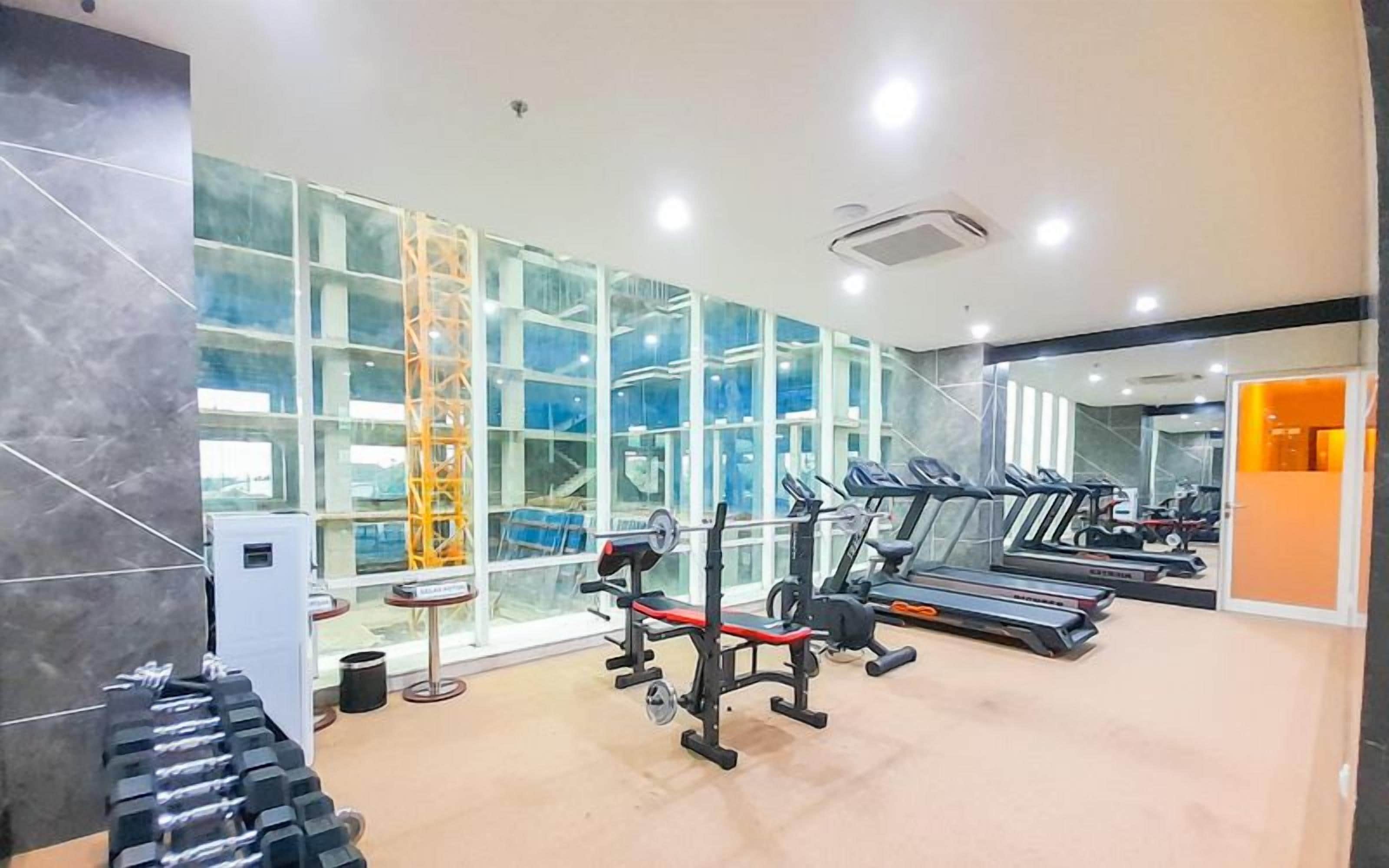 A gym with treadmills, weight machines, and dumbbells.