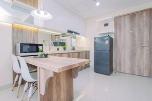 A modern kitchen with a central island, a built-in microwave, a refrigerator, and a dining area with chairs. - Smart And Great Choice 1Br At Apartment Pejaten Park Residence (Jakarta)