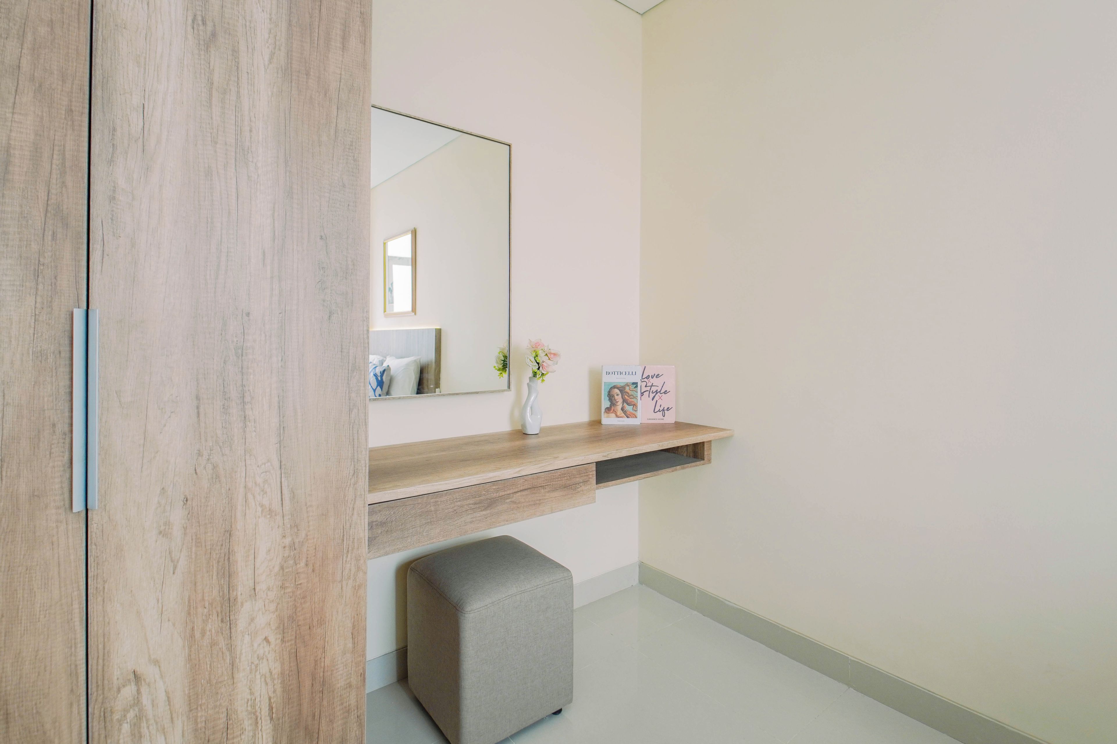 A modern bathroom with a wooden vanity, a mirror, a small bench, and a shelf with toiletries.
