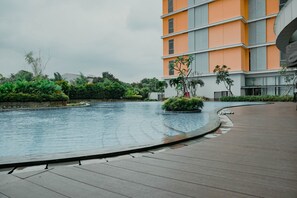 A modern building with a curved pool and a wooden deck. - Smart And Great Choice 1Br At Apartment Pejaten Park Residence (Jakarta)