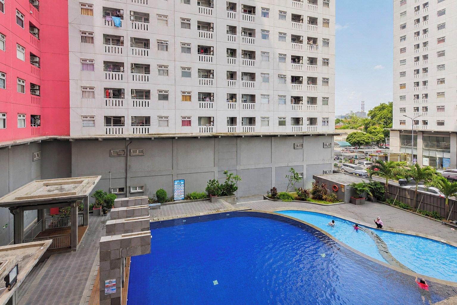 Un edificio residencial con varios balcones, piscina y un pequeño espacio exterior con plantas.