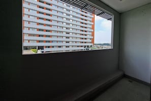 A view through a window of a multi-story building with a modern design, featuring a series of balconies and a clear sky in the background.