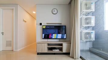 A modern living room with a flat-screen TV, a clock, and built-in air conditioning units.