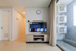 A modern living room with a flat-screen TV, a clock, and built-in air conditioning units.