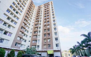 A high-rise residential building with multiple balconies, a flat facade, and a clear sky. - Happy Stay Studio At Apartment Menara Rungkut (Surabaya)