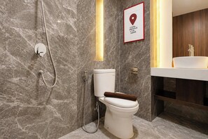 A modern bathroom with a marble wall, a toilet, a shower, and a sink with a wooden bath mat. - Generous Space Studio At The City Square Surabaya Apartment (Surabaya)