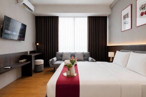 A hotel room with a bed, a TV, a desk, a chair, and a window with curtains. - Generous Space Studio At The City Square Surabaya Apartment (Surabaya)
