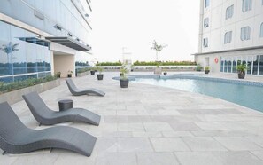 A rooftop pool area with lounge chairs and potted plants. - Generous Space Studio At The City Square Surabaya Apartment (Surabaya)
