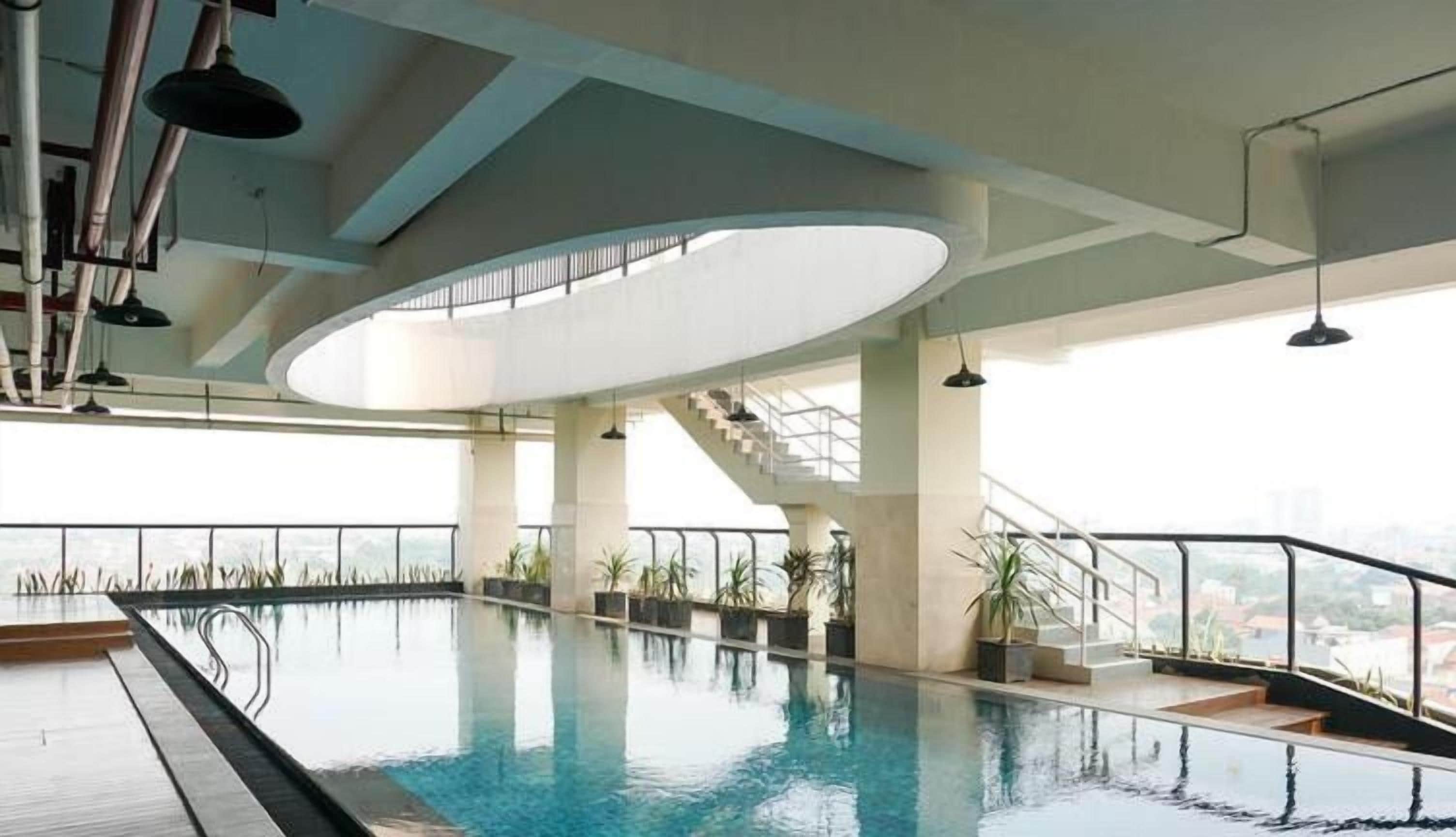 An indoor swimming pool with a view of the city, a staircase, and a modern ceiling design.