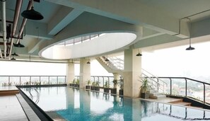 An indoor swimming pool with a view of the city, a staircase, and a modern ceiling design. - Cozy Living 1Br At Apartment Atlanta Residence (Depok)