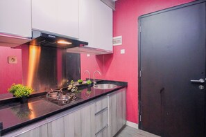 Une cuisine moderne dotée d’une hotte en acier inoxydable, d’un évier et d’une porte située à droite.