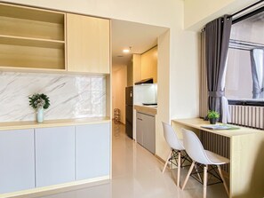 A modern kitchen with a marble backsplash, a built-in oven, and a dining area with two chairs. - Capacious And Warm 2Br At Apartment Meikarta District 1 (Cikarang)