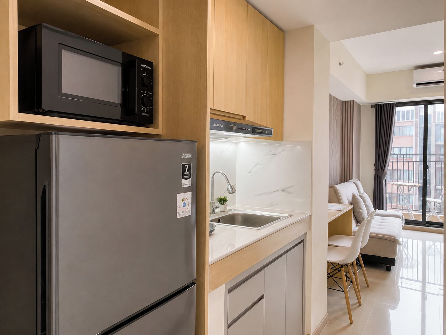 A compact kitchenette with a refrigerator, microwave, and modern stove.