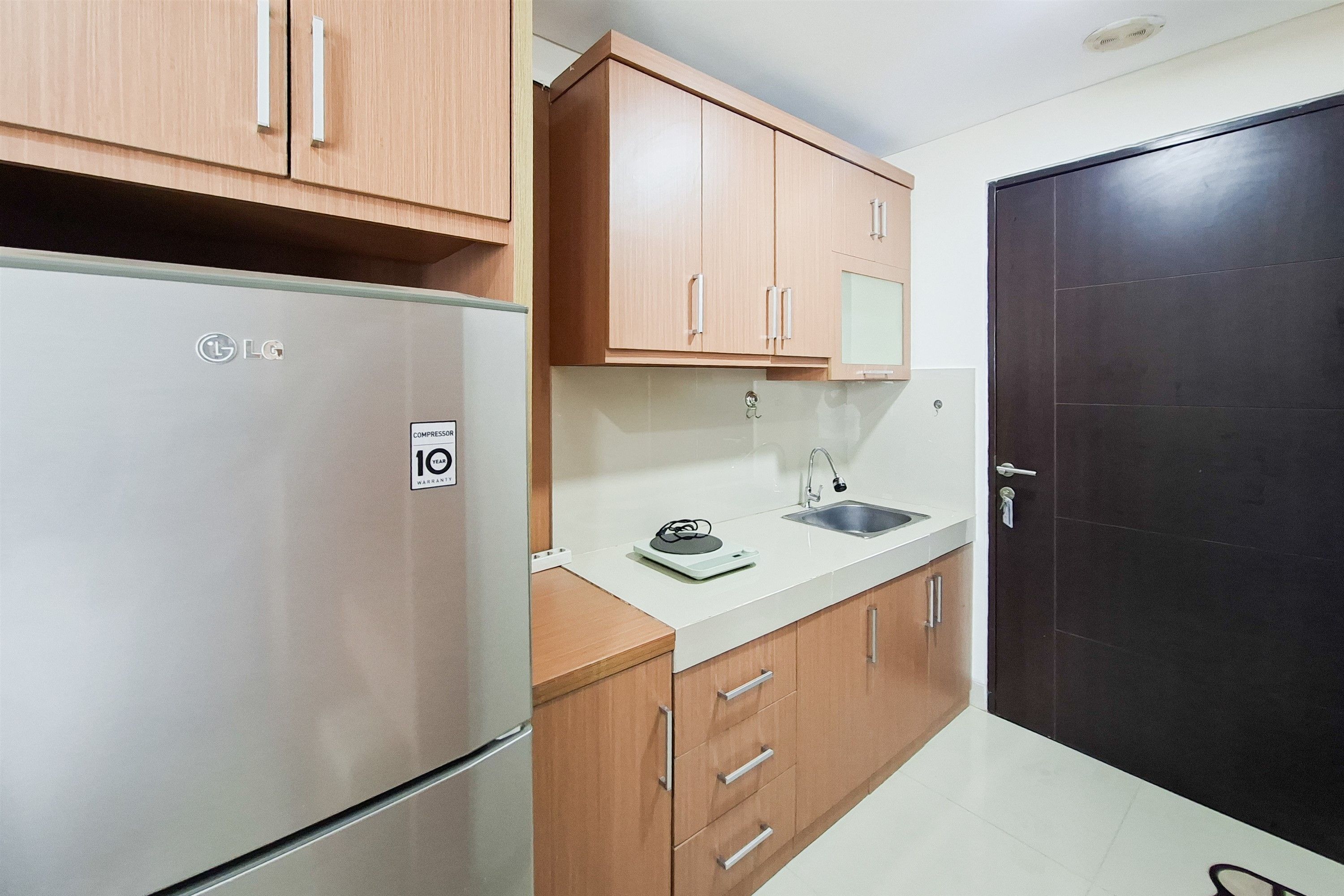 Una cocina compacta con refrigerador, lavamanos y armarios de madera.