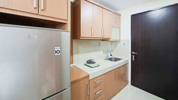 Una cocina compacta con refrigerador, lavamanos y armarios de madera.