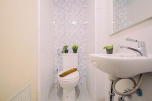 A bathroom with a toilet, a sink, and two potted plants. - Efficient Studio (No Kitchen) At Apartment Tokyo Riverside Pik 2 (Jakarta)