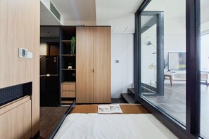 Een moderne slaapkamer met een groot raam, een bed, een kledingkast en een kleine plant.
